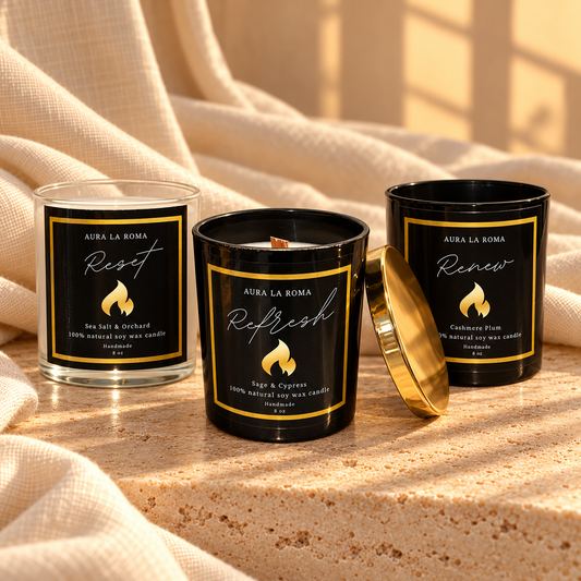 The Aura Reset Collection: Reset, Refresh and Renew candles together on warm stone with ivory linen.
