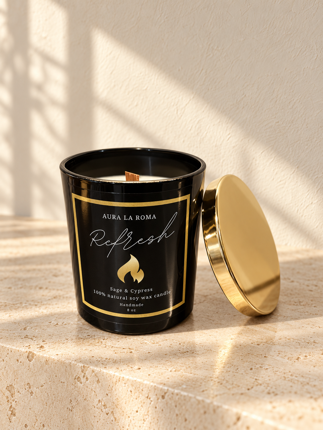 Refresh black candle with gold lid in a softly lit ivory limestone setting.