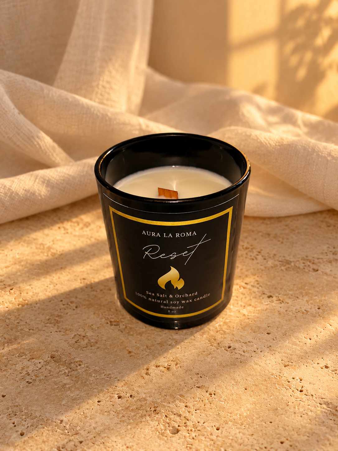 Top view of Reset black candle and wooden wick in a warm linen and stone ritual setting.